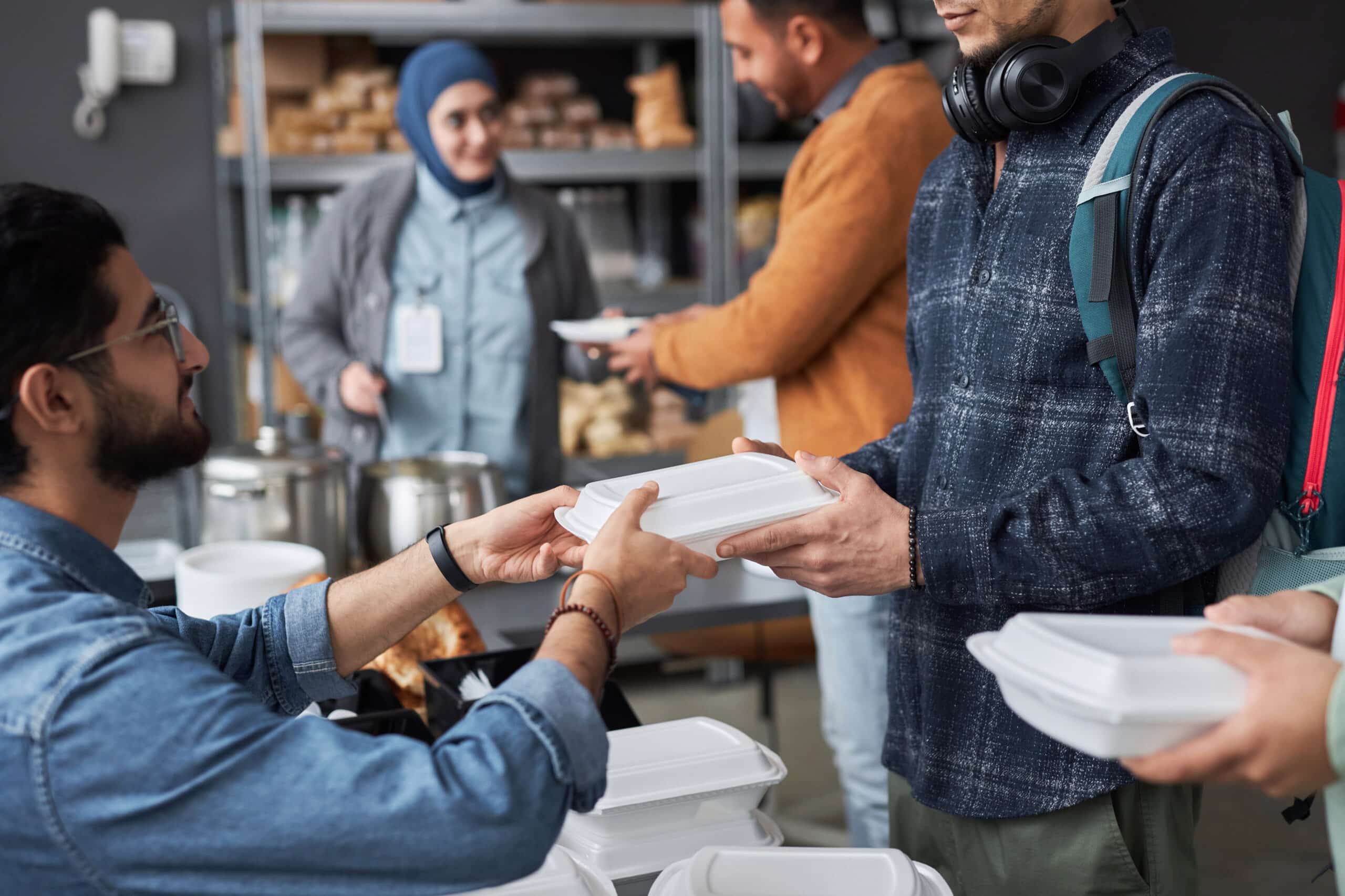 volunteer giving free food to middle eastern refugees standing in line