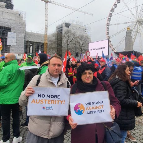 Rob and laura from the Social platform secretariat stand at a march with signs that read no more auterity