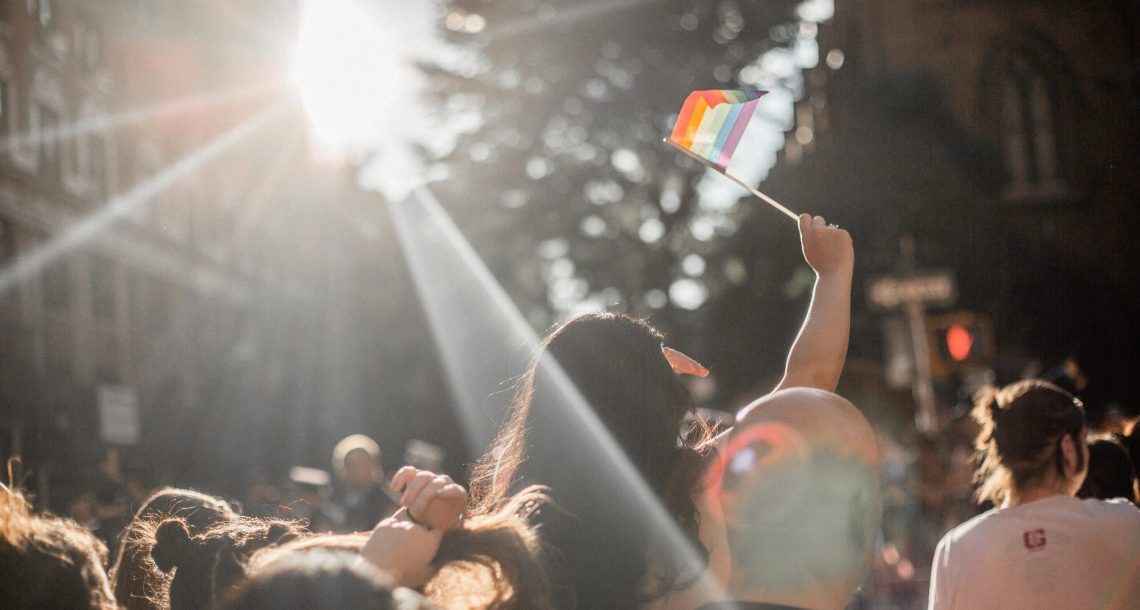 Crowd of people, young girl waving pride flag