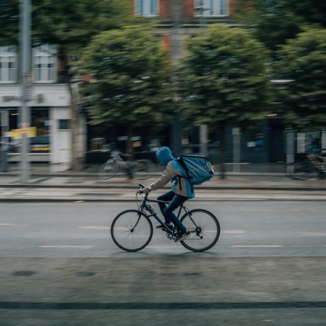 person on a bicycle on the street with a delivery box on their back